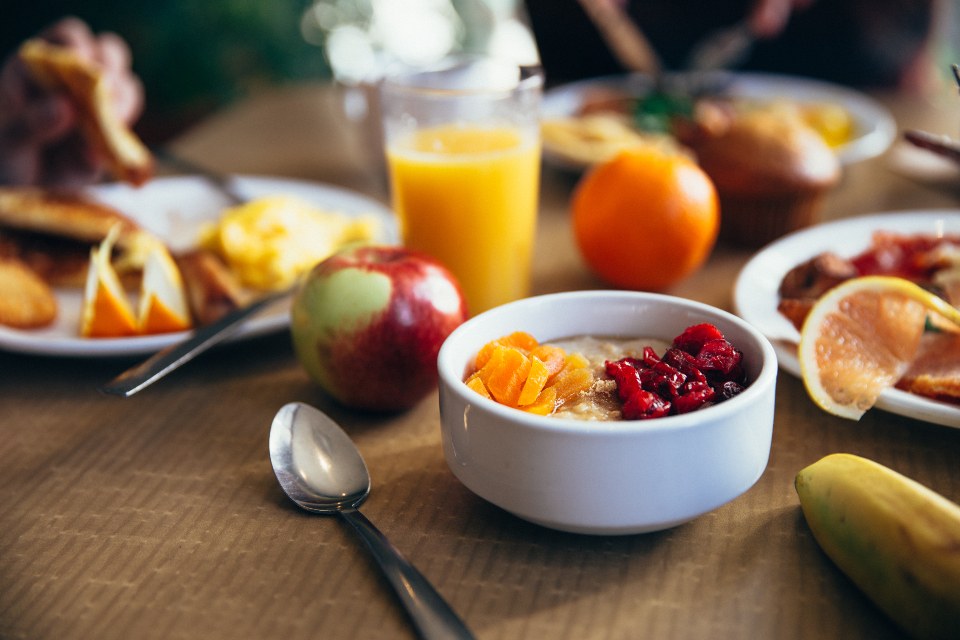 A breakfast table set with fruit, orange juice and a bowl of berries
