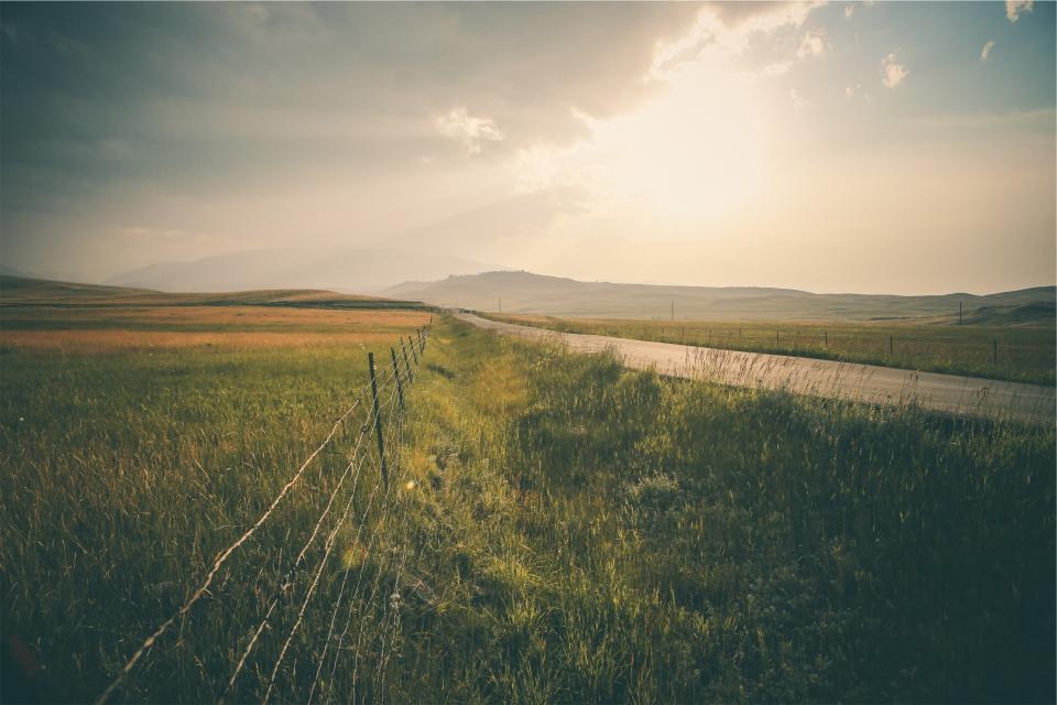Sunlight breaking through clouds over a countryside path